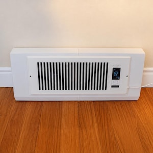 May include: A white rectangular register booster fan with a slatted front grille. The unit features a digital display screen on the right side showing the text AC INFINITY and the number 63, along with integrated control buttons and a power cord.