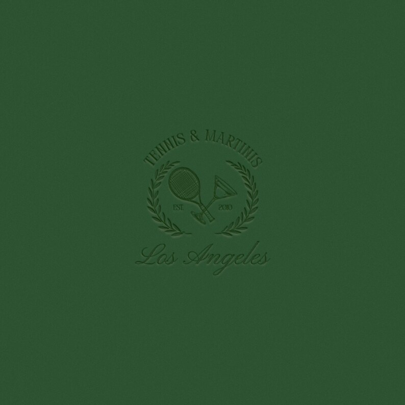 Op de afbeelding: Een groen logo met de tekst "Tennis & Martius" in een cirkel met een laurierkransontwerp. De tekst "Est. 2010" staat onder de krans. Twee gekruiste tennisrackets bevinden zich in de krans. De tekst "Los Angeles" staat onder de krans.