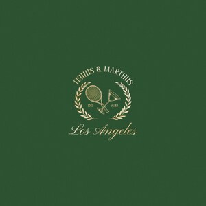 Op de afbeelding: Gouden logo op een groene achtergrond met de tekst "Tennis & Martinis" in een lauwerkrans met een tennisracket en een martini-glas erin. De tekst "Est. 2010" staat onder de krans en de tekst "Los Angeles" eronder.