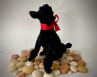 Naaldvilten zwarte poedel puppy zittend