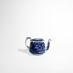 Op de afbeelding: Een blauw-witte keramische theepot met een landschapsontwerp. De theepot heeft een gebogen handvat, een tuit en een deksel. Het ontwerp is een klassiek blauw-wit patroon, met een gedetailleerde landschapsweergave.