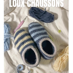 Peut inclure: Une paire de chaussons crochetés à rayures horizontales bleu foncé et crème, avec une bordure claire autour de l'ouverture. Le texte LOUX CHAUSSONS est visible en haut, accompagné de pelotes de laine, d'un crochet rose et d'un ruban à mesurer.