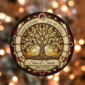 May include: A round, stained-glass style ornament featuring a central tree illustration with red and green accents. The text reads "United in Faith for 40 Years", "Steve & Sheila", and "1986 - 2026". It hangs from a gold cord against a blurred background.