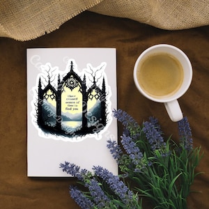 May include: A white sticker with a gothic arch design, featuring a landscape scene with the text "I have crossed oceans of time to find you." A cup of coffee and lavender sprigs are also present.