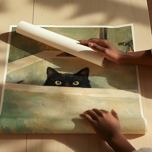 May include: A rolled white poster displaying a painting of a black cat with yellow eyes, peeking over a ledge. The artwork has a vintage aesthetic with muted green and beige tones. The poster is being held by two hands.