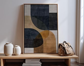 May include: Abstract art print in a wooden frame featuring geometric shapes in navy, tan, and gray. The artwork is displayed on a wooden bench with white vases, books, and a canvas bag.