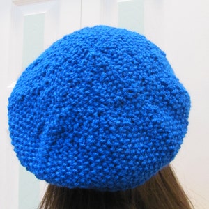 May include: A bright blue knitted beret hat. The hat is made of a soft, textured yarn and has a simple, classic design.