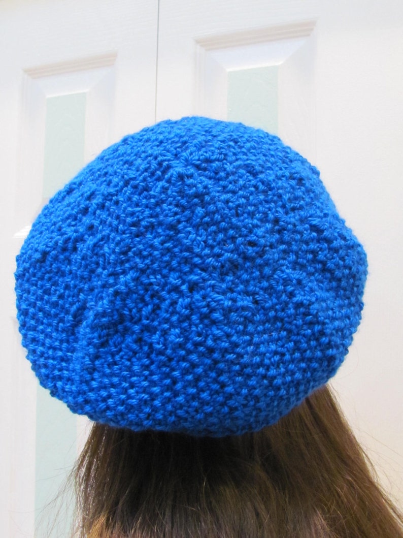 May include: A bright blue knitted beret hat. The hat is made of a soft, textured yarn and has a simple, classic design.