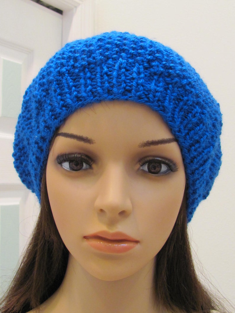 May include: A bright blue knitted beanie hat. The hat is made of a soft, textured yarn and has a simple, classic design.