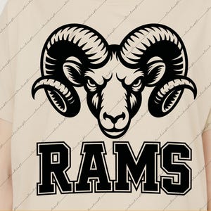 May include: A beige t-shirt featuring a black graphic of a ram's head with large curved horns and the word "RAMS" in a bold, blocky font. The design is a digital download file.