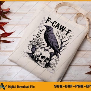 May include: A beige tote bag featuring a black raven perched on a skull, with the text "F-CAW-F". The design includes floral and branch elements. The bag has cream-colored handles and is suitable for carrying items.