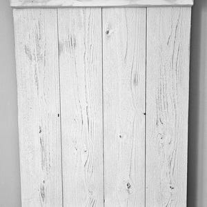 Op de afbeelding: Wit houten schuttingpaneel met twee horizontale latten. De schutting is gemaakt van verweerd hout met een witte verfbehandeling.