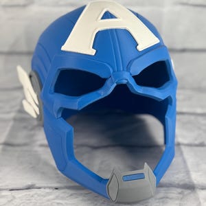 May include: Blue plastic Captain America helmet with a white "A" on the front. The helmet has a gray chin guard and eye holes.