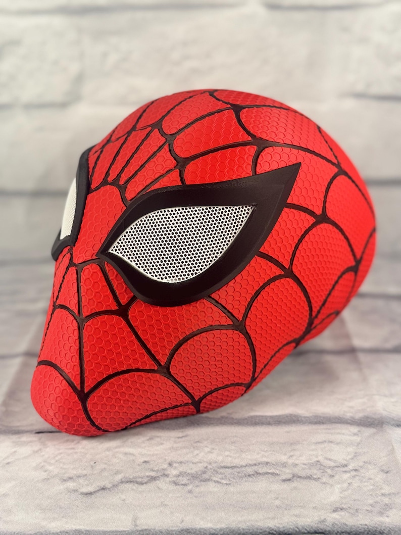 Puede incluir: M&aacute;scara de Spider-Man roja y negra con una cubierta de ojo de malla. La m&aacute;scara est&aacute; hecha de un material texturizado y tiene un dise&ntilde;o de telara&ntilde;a.