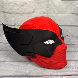 May include: A full-head mask featuring a bright red textured base with a prominent black eye and temple overlay. The design includes large, swept-back black side fins and white mesh eye coverings, creating a distinct profile for this cosplay accessory.