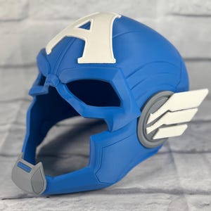May include: A blue plastic Captain America helmet with a white 'A' on the front and gray details. The helmet has a visor and a chin strap.