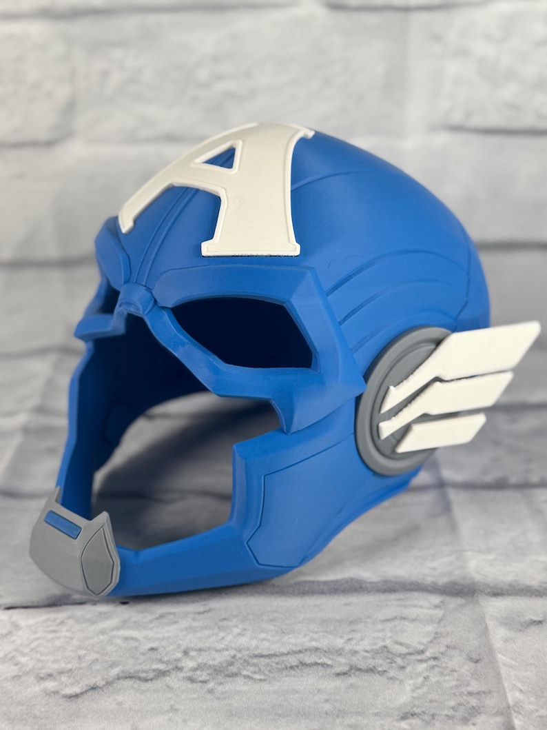 May include: A blue plastic Captain America helmet with a white 'A' on the front and gray details. The helmet has a visor and a chin strap.