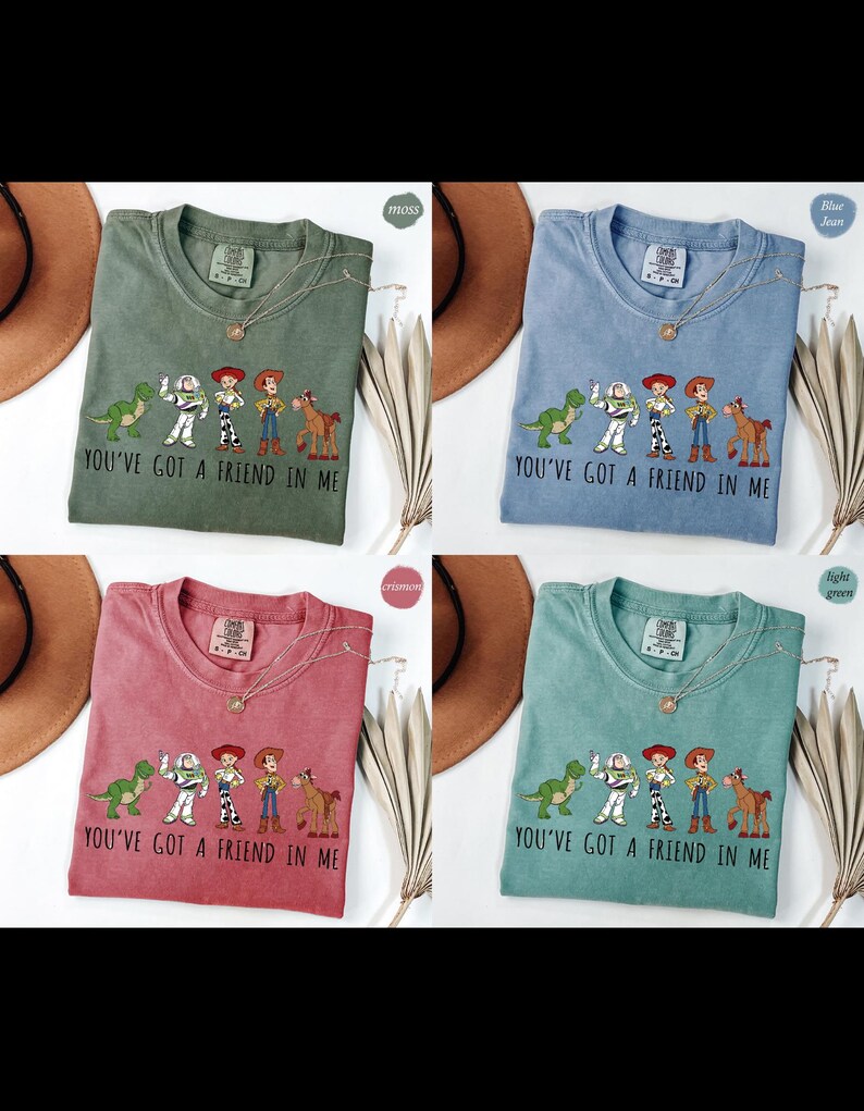 Puede incluir: Cuatro camisetas en verde musgo, azul vaquero, carmes&iacute; y verde claro, cada una con un gr&aacute;fico de personajes de dibujos animados y el texto "YOU'VE GOT A FRIEND IN ME." Cada camiseta tiene un collar.