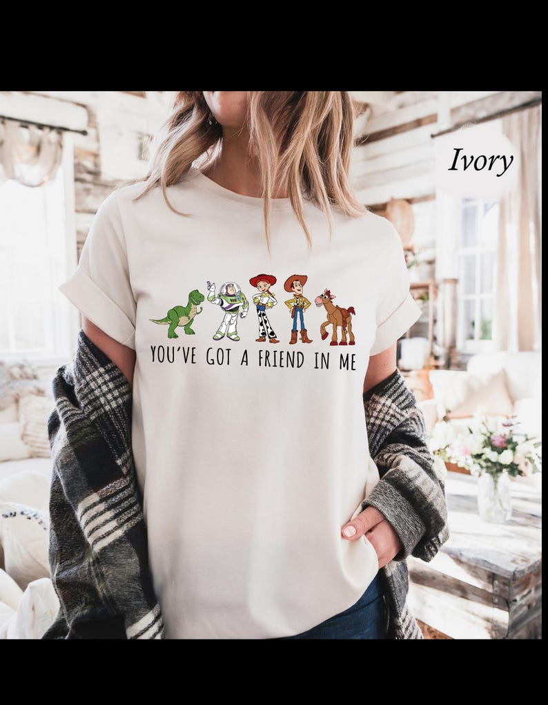 Puede incluir: Camiseta de color marfil con un gr&aacute;fico de personajes de una pel&iacute;cula de animaci&oacute;n popular. El dise&ntilde;o incluye un dinosaurio verde, un guardabosques espacial, dos vaqueros y un caballo, con el texto "YOU'VE GOT A FRIEND IN ME".