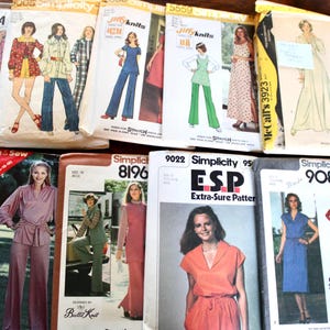 May include: A collection of vintage sewing patterns featuring illustrations of various clothing styles. The patterns showcase designs from the 1970s and 1980s, with a variety of dresses, pantsuits, and separates. The patterns are in their original packaging.