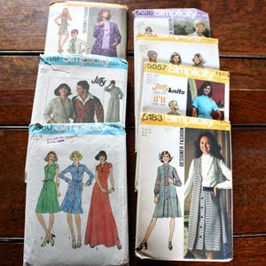 May include: A collection of vintage Simplicity sewing patterns. The patterns feature illustrations of dresses, jackets, and other garments. The covers display the "Simplicity" logo and the words "Designer Fashion" and "Jiffy Knits".