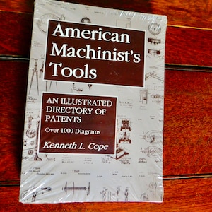 Può includere: Un libro intitolato "American Machinist's Tools: An Illustrated Directory of Patents" di Kenneth L. Cope. La copertina presenta uno sfondo marrone con testo bianco e oltre 1000 diagrammi di strumenti.