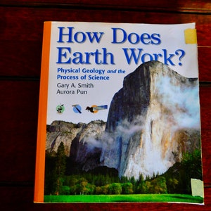 May include: A book titled "How Does Earth Work?" with a picture of a large rock formation on the cover. The book is about physical geology and the process of science. The authors are Gary A. Smith and Aurora Pun.