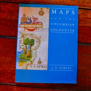 Puede incluir: Un libro azul titulado "MAPS AND THE COLUMBIAN ENCOUNTER" de J.B. Harley. La portada presenta un mapa antiguo con una representación de un barco y una masa de tierra etiquetada como "BRASIL".