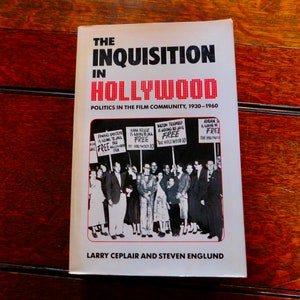 May include: A black and white photo of a group of people holding signs that say "FREE". The book cover is titled "The Inquisition in Hollywood: Politics in the Film Community, 1930-1960" by Larry Ceplair and Steven Englund.