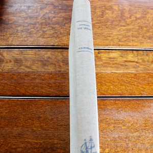 May include: A vintage book spine with the title "Modelling The 'Irene'" and author's name. The book has a light beige cover with blue text and a small illustration of a sailboat. The book is set against a wooden background.