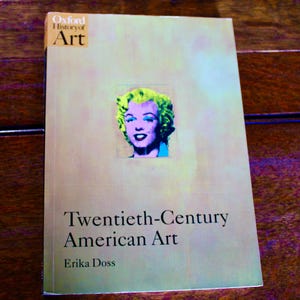 May include: A book titled "Twentieth-Century American Art" by Erika Doss. The cover features a pop art portrait of Marilyn Monroe with green, purple, and blue hues. The book is part of the "Oxford History of Art" series.