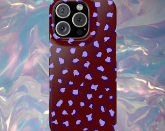 Puede incluir: Una funda para smartphone con fondo granate oscuro y un patrón repetitivo de manchas irregulares de color morado claro. La funda tiene un recorte para un sistema de cámara de triple lente en la parte superior izquierda y cubre la parte trasera y los lados.