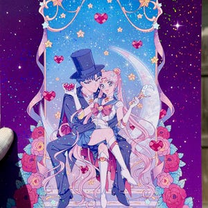 May include: A vibrant illustration features a couple seated on a crescent moon, surrounded by stars and hearts. The characters are dressed in detailed, colorful outfits, with a backdrop of roses and a starry sky. The artwork has a romantic theme.