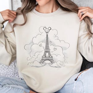 Disney meets Paris in this magical tee featuring the Eiffel Tower with a classic Mickey Mouse head perched on top. Perfect for Disneyland Paris vacations, this design blends iconic French landmarks with beloved Disney charm. Ideal for families, travel lovers, or Disney fans making memories in the City of Light. A stylish and fun shirt for park visits, photo ops, or post-trip souvenirs.