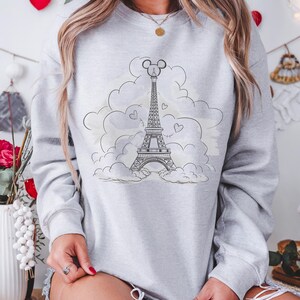 Disney meets Paris in this magical tee featuring the Eiffel Tower with a classic Mickey Mouse head perched on top. Perfect for Disneyland Paris vacations, this design blends iconic French landmarks with beloved Disney charm. Ideal for families, travel lovers, or Disney fans making memories in the City of Light. A stylish and fun shirt for park visits, photo ops, or post-trip souvenirs.