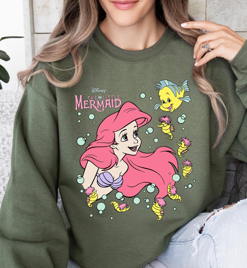 Retro-style Disney Little Mermaid shirt featuring Princess Ariel, perfect for girls’ trips, family vacations, or matching outfits at Walt Disney World. This playful tee or hoodie showcases nostalgic design elements with seashells, waves, and classic Ariel artwork. Great for park days, Disney cruise wear, or fans of the original Disney princess with a love for under-the-sea adventure and magical memories.