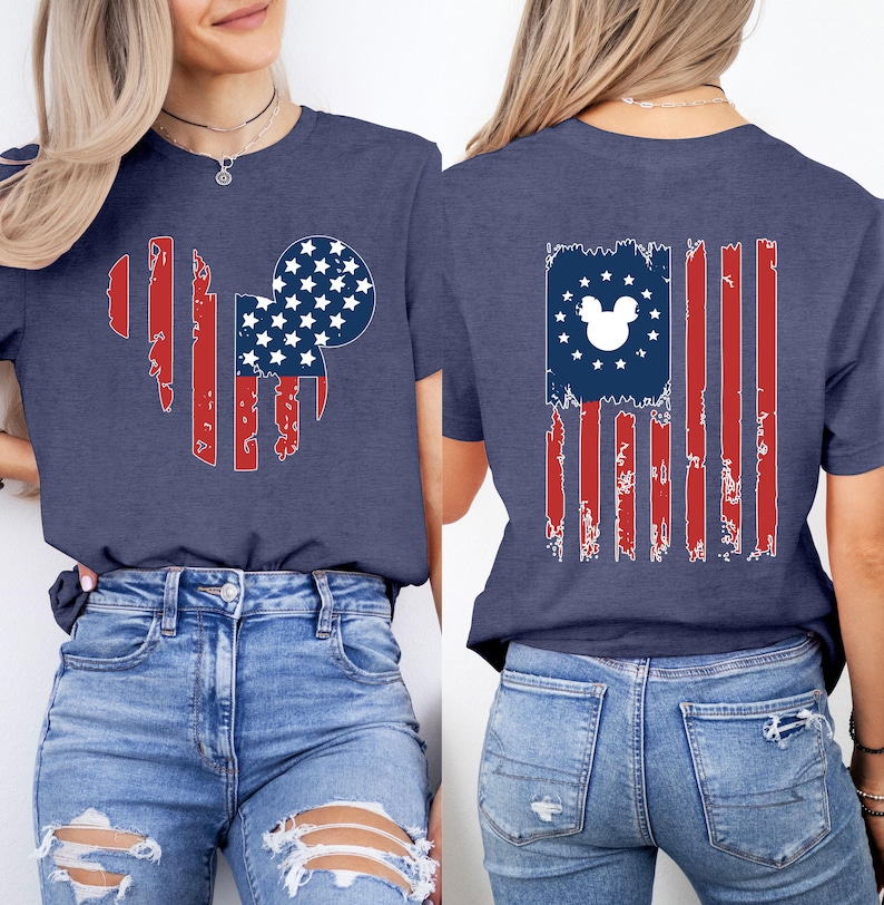 May include: Navy blue t-shirt with a distressed American flag design incorporating a Mickey Mouse silhouette. The front features a Mickey head shape with red stripes and a blue circle filled with white stars. The back has a flag design with a Mickey head.