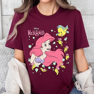 Retro-style Disney Little Mermaid shirt featuring Princess Ariel, perfect for girls’ trips, family vacations, or matching outfits at Walt Disney World. This playful tee or hoodie showcases nostalgic design elements with seashells, waves, and classic Ariel artwork. Great for park days, Disney cruise wear, or fans of the original Disney princess with a love for under-the-sea adventure and magical memories.