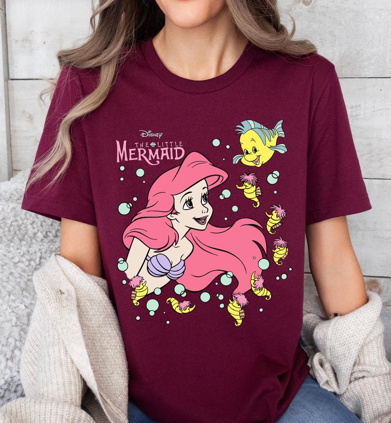 Retro-style Disney Little Mermaid shirt featuring Princess Ariel, perfect for girls’ trips, family vacations, or matching outfits at Walt Disney World. This playful tee or hoodie showcases nostalgic design elements with seashells, waves, and classic Ariel artwork. Great for park days, Disney cruise wear, or fans of the original Disney princess with a love for under-the-sea adventure and magical memories.