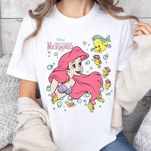 Retro-style Disney Little Mermaid shirt featuring Princess Ariel, perfect for girls’ trips, family vacations, or matching outfits at Walt Disney World. This playful tee or hoodie showcases nostalgic design elements with seashells, waves, and classic Ariel artwork. Great for park days, Disney cruise wear, or fans of the original Disney princess with a love for under-the-sea adventure and magical memories.