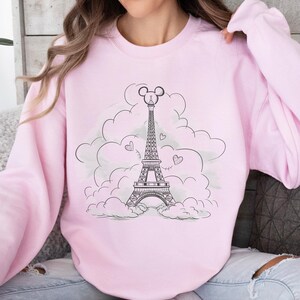 Disney meets Paris in this magical tee featuring the Eiffel Tower with a classic Mickey Mouse head perched on top. Perfect for Disneyland Paris vacations, this design blends iconic French landmarks with beloved Disney charm. Ideal for families, travel lovers, or Disney fans making memories in the City of Light. A stylish and fun shirt for park visits, photo ops, or post-trip souvenirs.