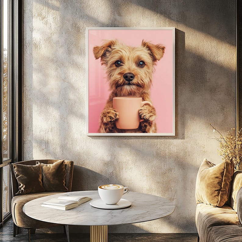 May include: A framed print featuring a Yorkshire Terrier dog holding a peach-colored mug against a pink background. The dog has brown fur and is looking directly at the viewer. The print is displayed on a textured gray wall.