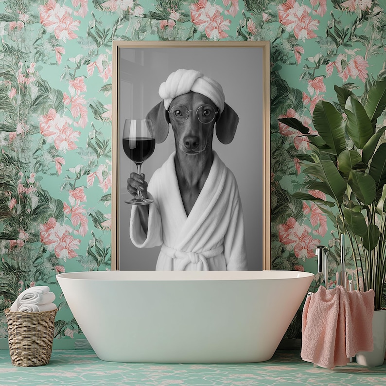 Op de afbeelding: Zwart-witfoto van een hond die een witte badjas draagt en een glas wijn vasthoudt. De hond bevindt zich in een badkamer met een wit bad en een groene bloemenbehang.