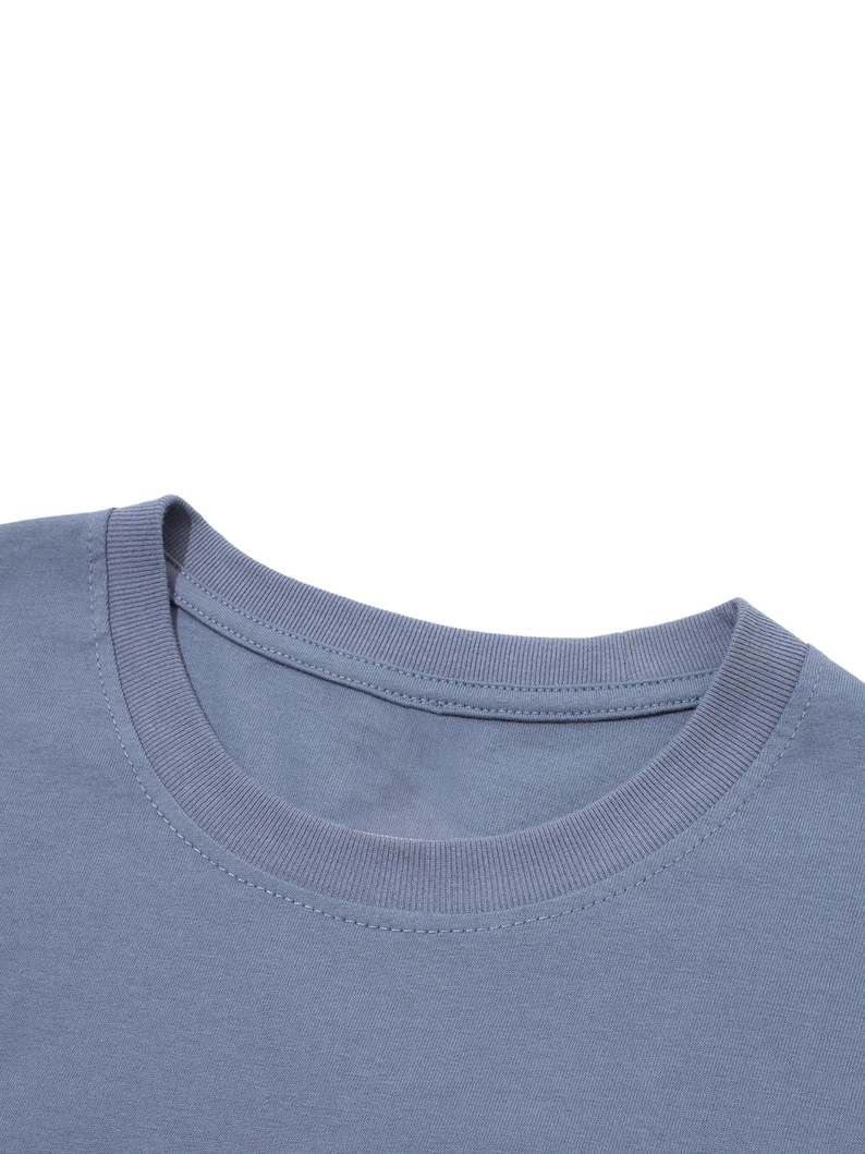 Close-up view of the ribbed collar on a blue-grey cotton t-shirt against a white background.