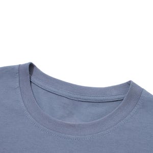 Close-up view of the ribbed collar and neckline of a blue-gray t-shirt against a white background.