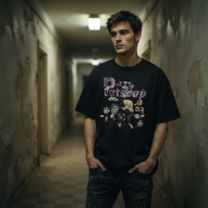 Model wearing the black Petscop bootleg tee in an atmospheric hallway showing the oversized relaxed fit and chest graphic.