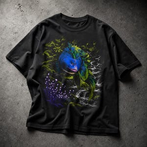 Può includere: T-shirt nero con una grafica colorata di una creatura blu e verde in un ambiente giungla. Il design include una cascata, piante viola luminose e fogliame. La maglietta è realizzata in materiale morbido.