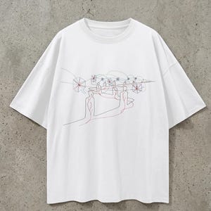 Könnte beinhalten: Weißes T-Shirt mit minimalistischem Strichdesign. Das Kunstwerk zeigt Figuren, die durch rote Linien verbunden sind, mit geometrischen Formen und zusätzlichen roten und schwarzen Linien. Das Shirt hat einen Rundhalsausschnitt und kurze Ärmel.