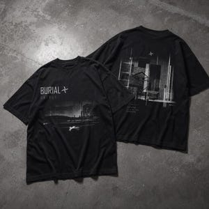 Puede incluir: Dos camisetas negras con un diseño gráfico desgastado. La parte delantera de la primera camiseta presenta el texto "BURIAL UNTRUE" sobre una imagen en escala de grises de un edificio y un paisaje. La parte trasera de la segunda camiseta tiene un diseño arquitectónico similar.
