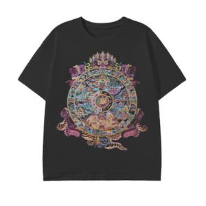 May include: Black t-shirt featuring a colorful, ornate circular design with intricate details. The design includes shades of purple, gold, blue, and pink, with a central circular element. The shirt has short sleeves and a crew neck.